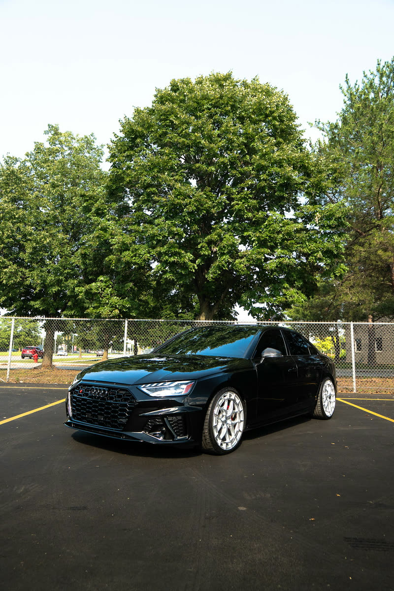 Black Audi sedan with silver wheels on an asphalt lot