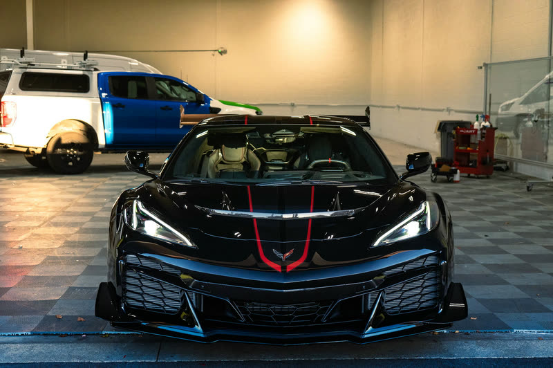 Black Corvette Z06 with red stripes inside a garage bay
