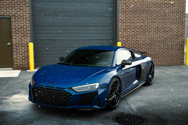 Blue Audi R8 in front of a brick garage door
