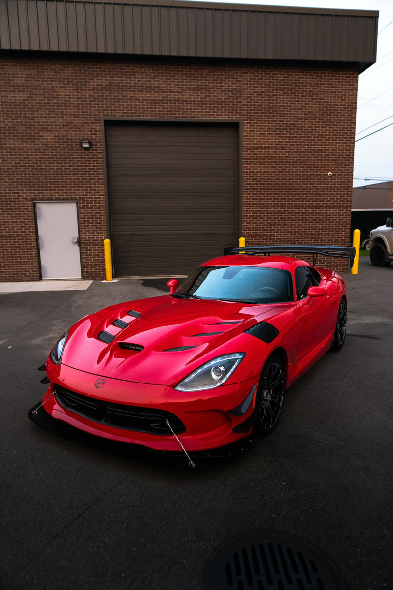 Red Dodge Viper ACR in front of a brick garage