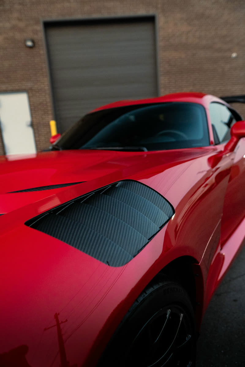 Red sports car hood with black vents, close up