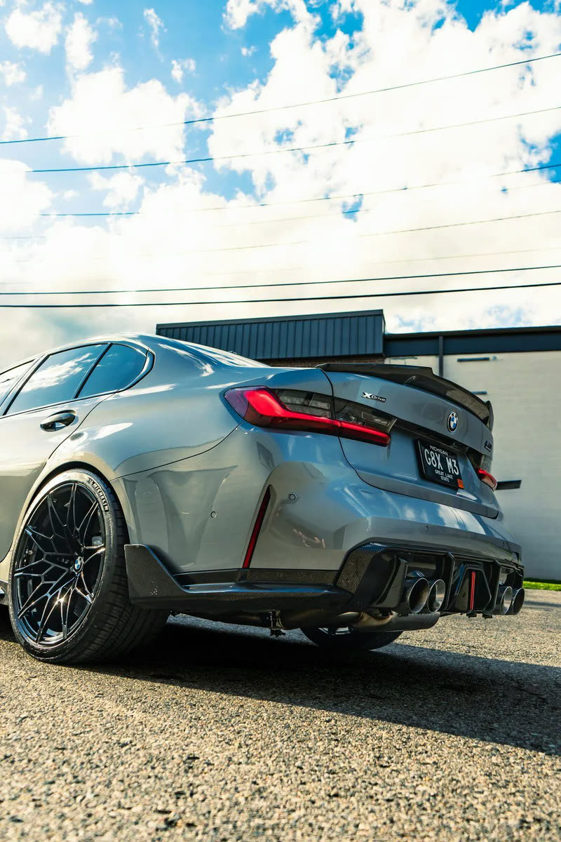 Grey BMW M3 Competition, rear three-quarter view with a carbon wing